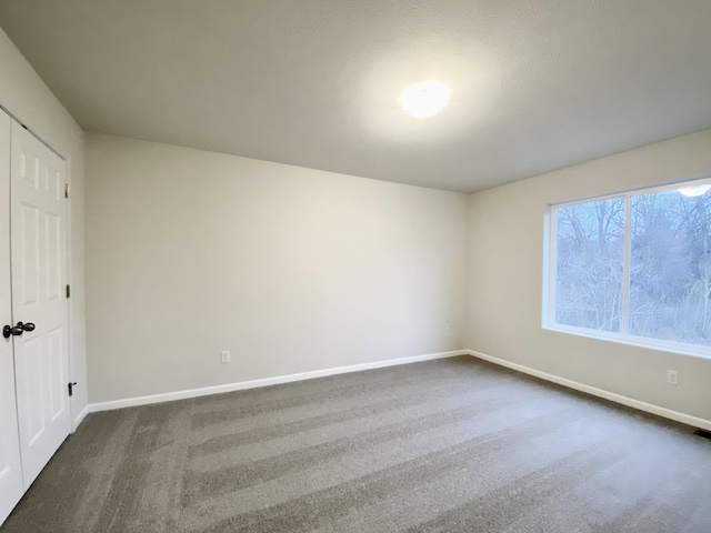 unfurnished bedroom with dark colored carpet and baseboards