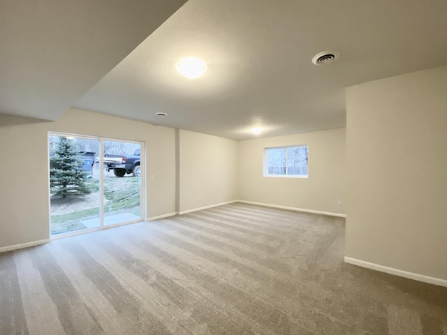 carpeted empty room featuring baseboards and visible vents