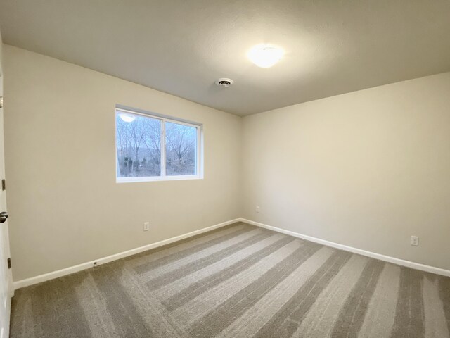 unfurnished room featuring carpet, visible vents, and baseboards