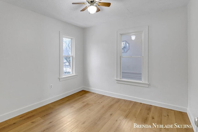 spare room featuring light wood-style flooring, baseboards, ceiling fan, and a textured ceiling