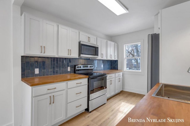 kitchen featuring light wood finished floors, tasteful backsplash, butcher block countertops, and appliances with stainless steel finishes