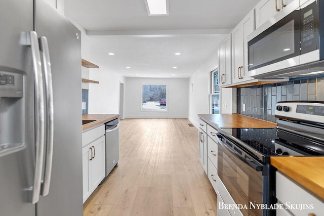 kitchen with stainless steel appliances, decorative backsplash, white cabinetry, butcher block countertops, and light wood-type flooring