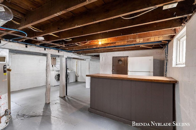 basement featuring freestanding refrigerator, gas water heater, and washer and clothes dryer