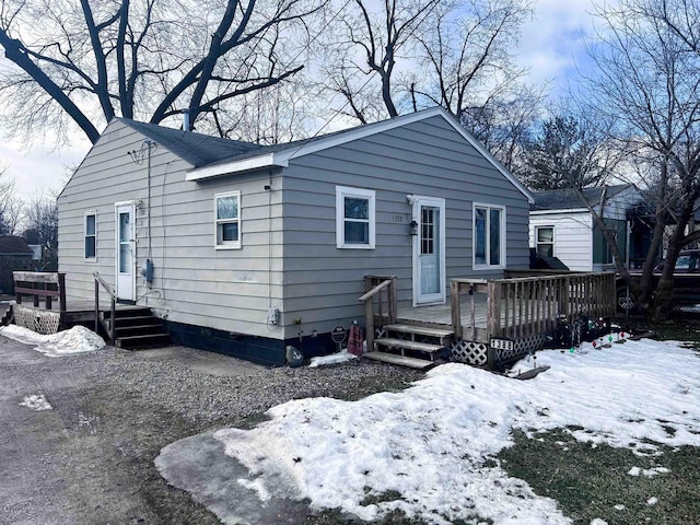 snow covered rear of property featuring a wooden deck