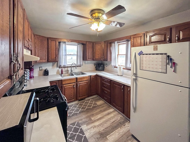 kitchen with freestanding refrigerator, a sink, black gas stove, plenty of natural light, and under cabinet range hood