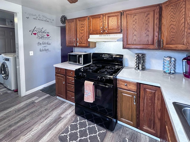 kitchen featuring light wood-style flooring, under cabinet range hood, black gas stove, light countertops, and stainless steel microwave