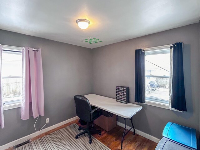 office space featuring baseboards, visible vents, and wood finished floors