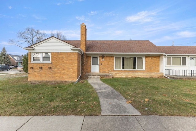 ranch-style house featuring roof with shingles, a chimney, a front lawn, and brick siding