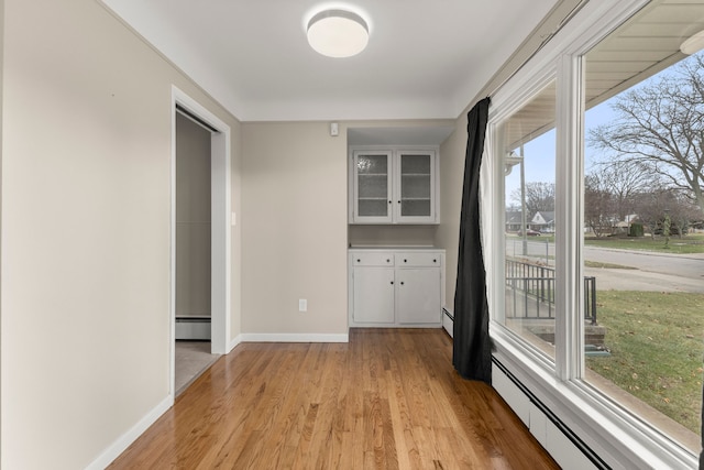 interior space featuring a baseboard heating unit, a baseboard radiator, light wood-style floors, and baseboards