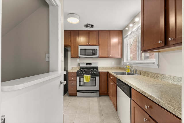 kitchen featuring light tile patterned flooring, a sink, visible vents, light countertops, and appliances with stainless steel finishes