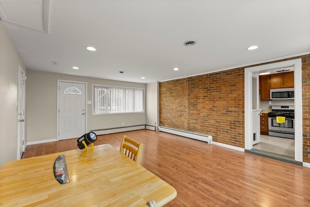 dining room featuring light wood-style floors, brick wall, a baseboard heating unit, and recessed lighting