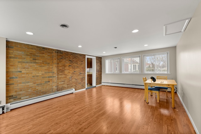 interior space with a baseboard radiator, visible vents, brick wall, and wood finished floors