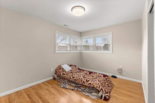 bedroom featuring light wood finished floors, visible vents, and baseboards