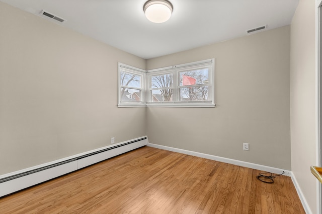 empty room featuring a baseboard heating unit, visible vents, light wood-style floors, and baseboards