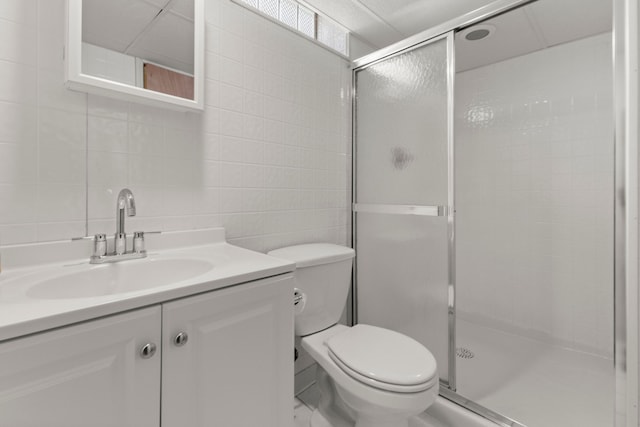 full bathroom featuring toilet, vanity, a shower stall, and tile walls