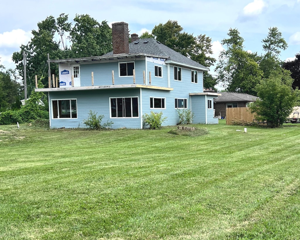 back of house with a chimney and a yard