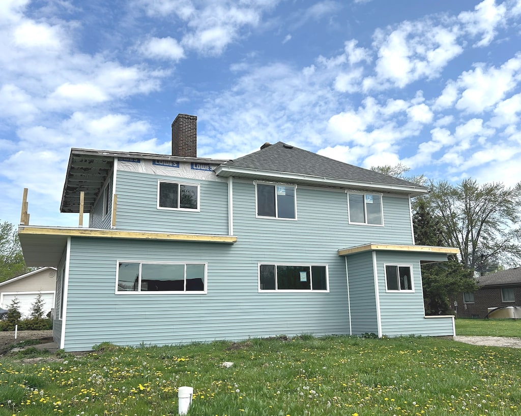 back of house featuring a yard and a chimney