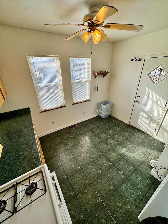 interior space featuring baseboards, visible vents, and a ceiling fan