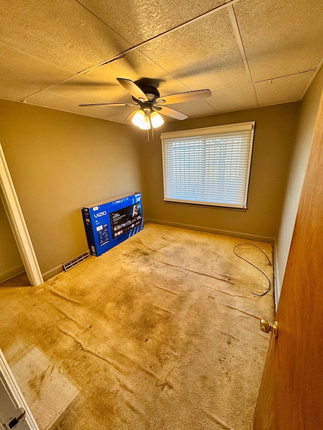 interior space featuring ceiling fan, carpet flooring, a paneled ceiling, and baseboards