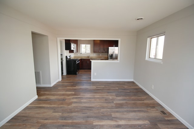 unfurnished living room featuring dark wood finished floors, visible vents, and baseboards