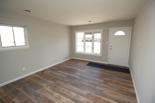 foyer entrance featuring visible vents, baseboards, dark wood-type flooring, and a wealth of natural light