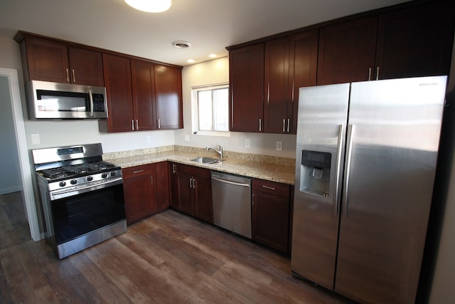 kitchen featuring visible vents, light stone counters, dark wood-style flooring, stainless steel appliances, and a sink