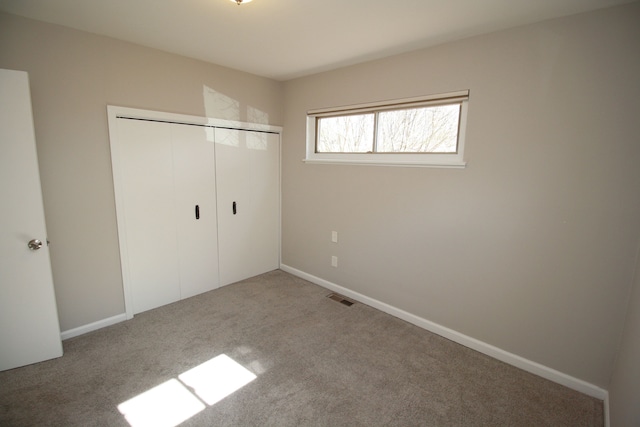 unfurnished bedroom with carpet floors, a closet, visible vents, and baseboards