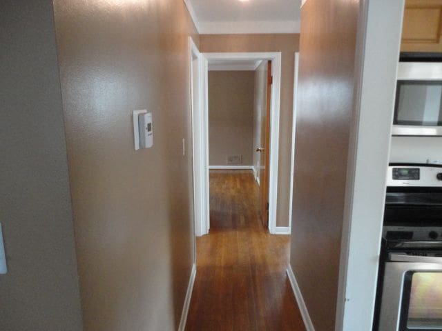 corridor with baseboards and wood finished floors