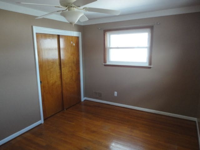 unfurnished bedroom with ceiling fan, a closet, baseboards, and wood finished floors