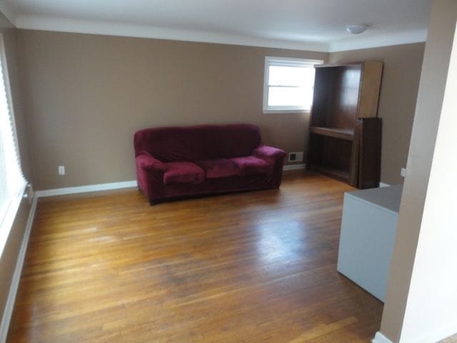 living area featuring ornamental molding, baseboards, and wood finished floors