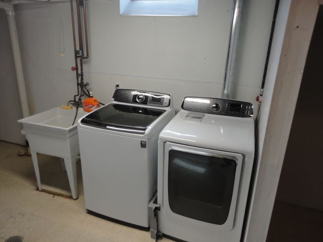 laundry room featuring laundry area, a sink, light floors, and separate washer and dryer