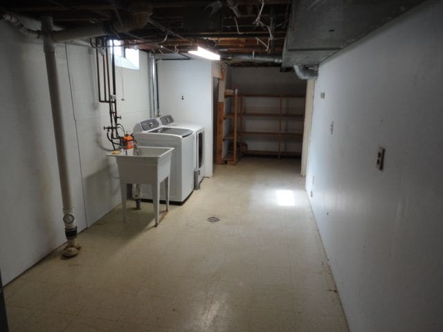 below grade area featuring washer and clothes dryer, a sink, and tile patterned floors