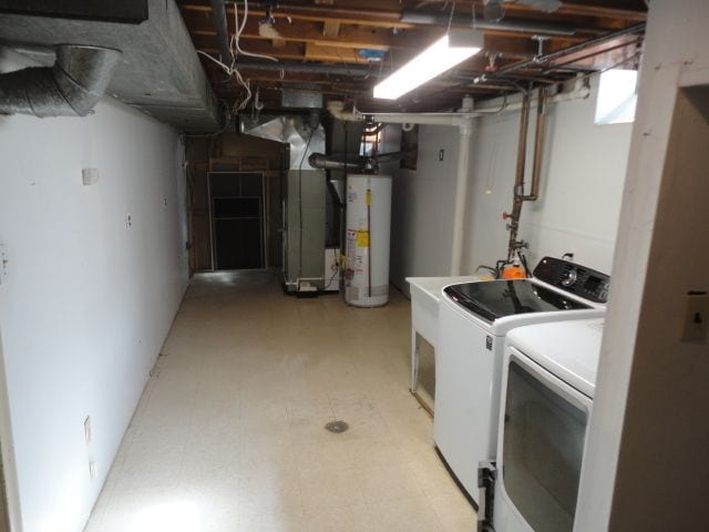 clothes washing area featuring gas water heater, laundry area, independent washer and dryer, heating unit, and light floors