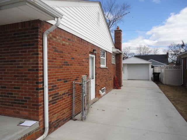 view of side of property with an outbuilding, concrete driveway, brick siding, and a garage