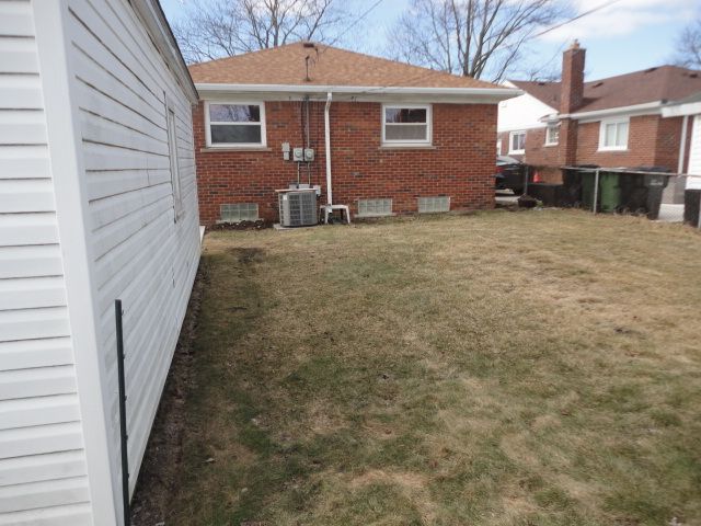 rear view of property with brick siding, a lawn, and cooling unit