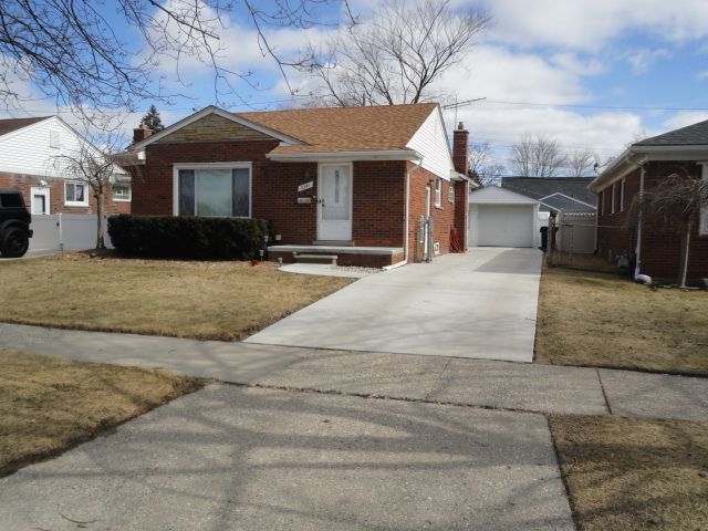 bungalow-style house with brick siding, an outdoor structure, fence, a front lawn, and a chimney