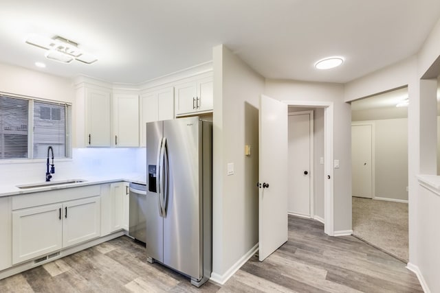 kitchen featuring stainless steel appliances, light countertops, visible vents, white cabinetry, and a sink