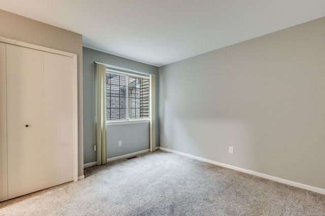 unfurnished bedroom featuring carpet floors, baseboards, visible vents, and a closet