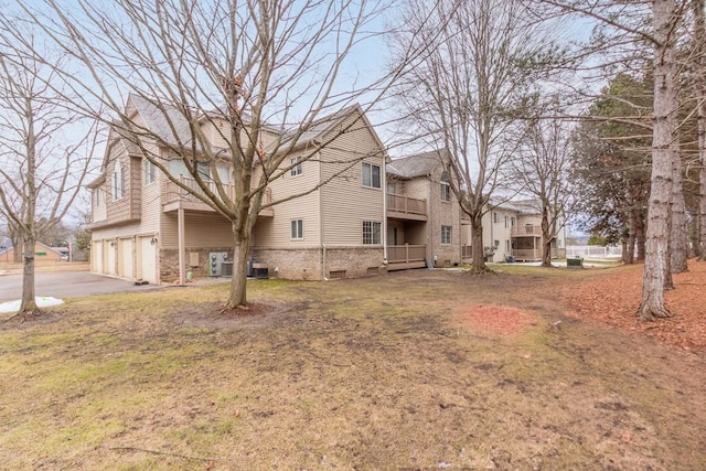 view of home's exterior featuring aphalt driveway, brick siding, a balcony, and an attached garage