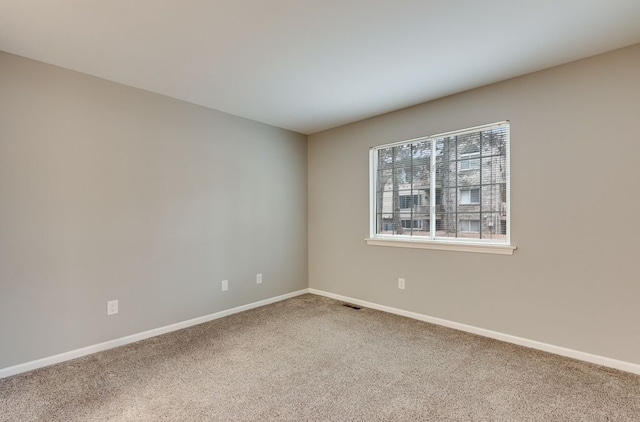 carpeted spare room with visible vents and baseboards