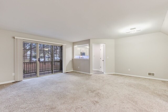 carpeted spare room with lofted ceiling, visible vents, and baseboards