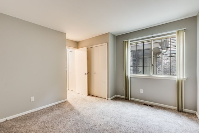 unfurnished bedroom with carpet, visible vents, baseboards, and a closet