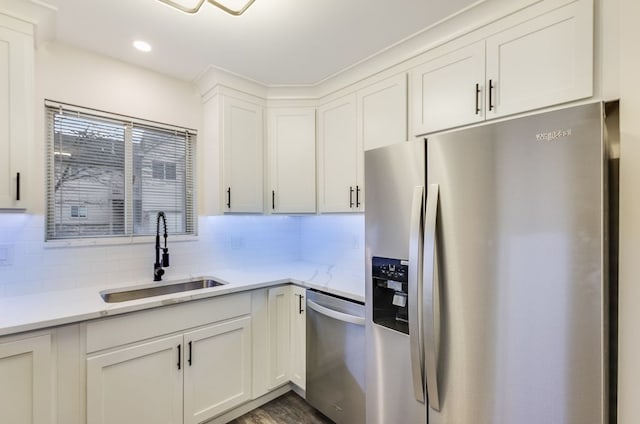 kitchen with light stone counters, stainless steel appliances, tasteful backsplash, white cabinets, and a sink