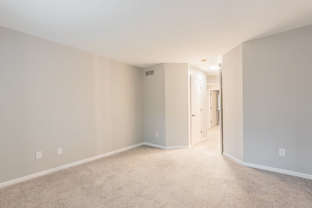 unfurnished room featuring visible vents, light carpet, and baseboards