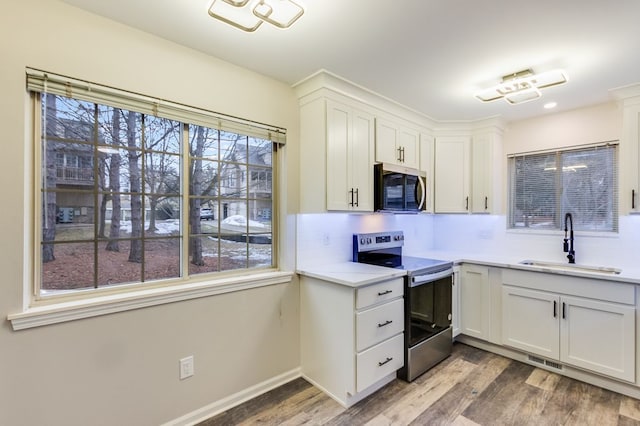 kitchen with visible vents, backsplash, a sink, wood finished floors, and stainless steel range with electric stovetop