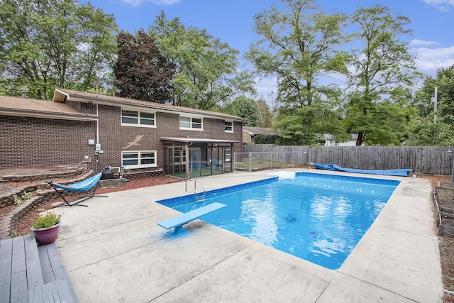 view of pool with a fenced in pool, a sunroom, a fenced backyard, a patio area, and a diving board