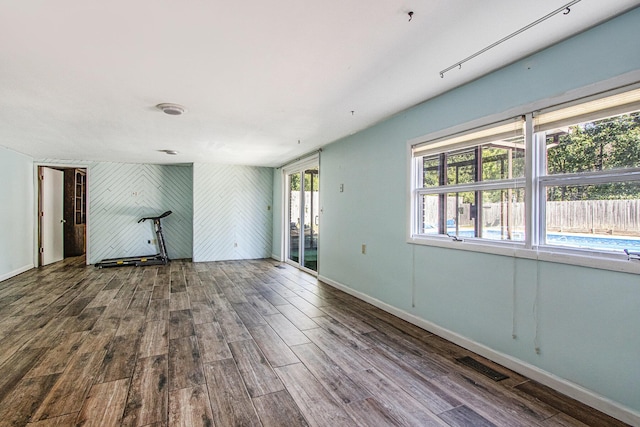 empty room with wood finished floors, visible vents, and baseboards