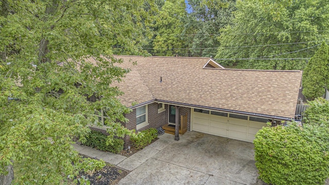 view of front of home with driveway, a shingled roof, and an attached garage