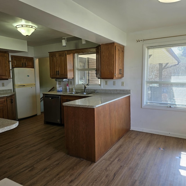 kitchen with a peninsula, dark wood-style flooring, a sink, freestanding refrigerator, and dishwasher