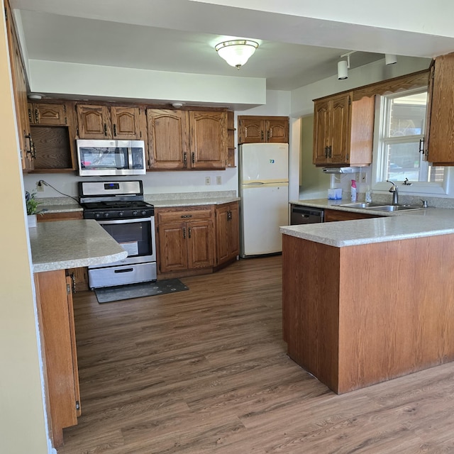 kitchen featuring stainless steel appliances, light countertops, dark wood-type flooring, and a sink